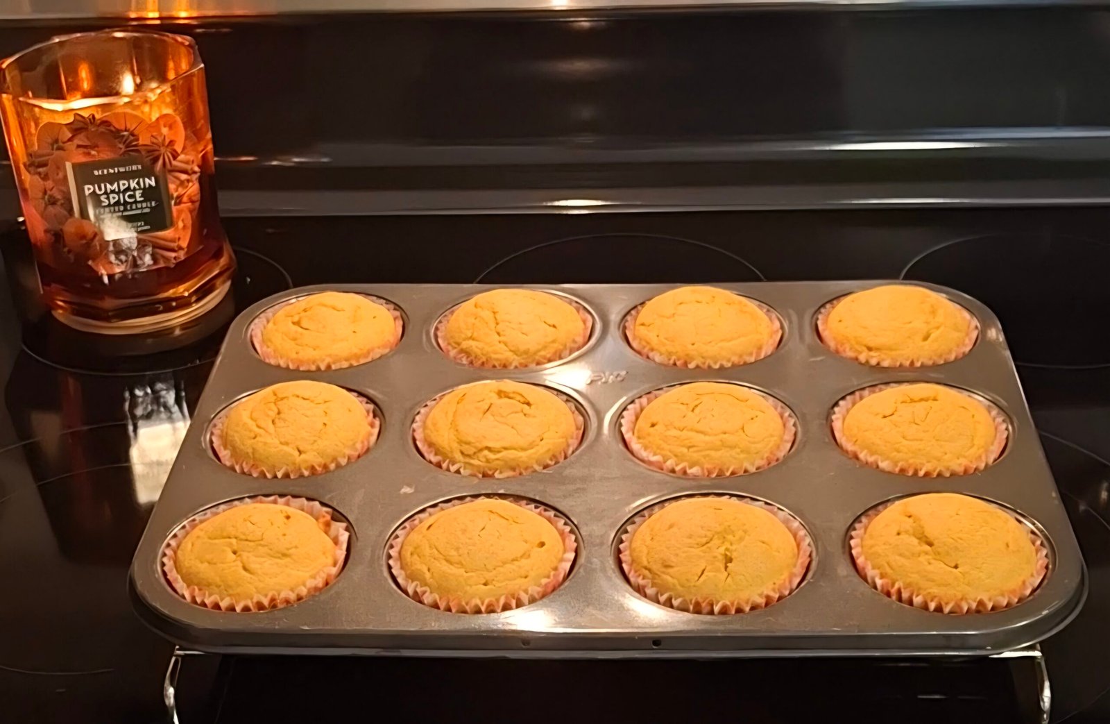 Pumpkin muffins with sourdough discard cooling in a baking pan on the stove.