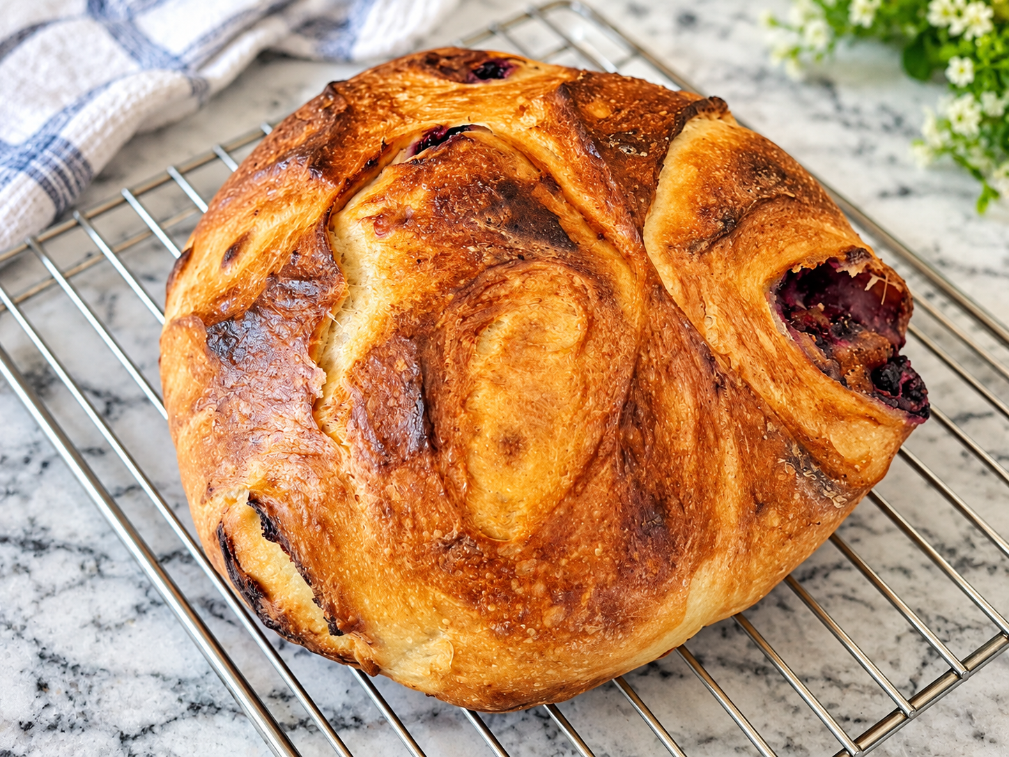 Sliced blueberry lemon cream cheese sourdough bread on a wooden cutting board, showing golden bread layers, creamy filling, and baked blueberries.